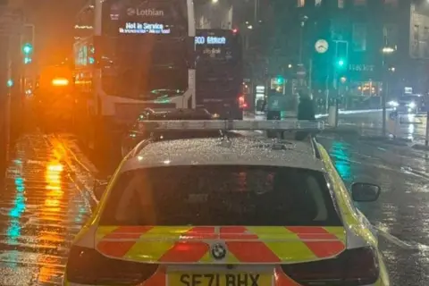 Breaking News and Crime in Edinburgh, The Lothians and Fife A police car is in the foreground. In the background is the back of the bus that was involved in the incident.