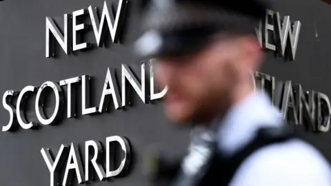 EPA The blurred profile of a police officer in front of a New Scotland Yard sign