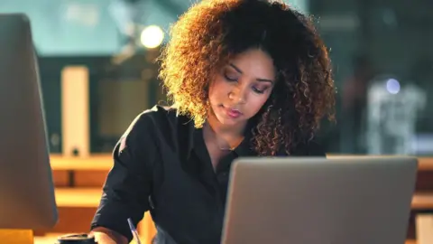 Getty Images Woman looking at computer and phone