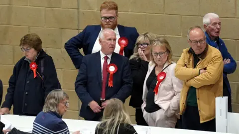 Labour party activists look on as ballot papers are counted for the 2026 Essex County Council election at Clacton Leisure Centre in Essex