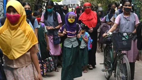 AFP via Getty Images Students arrive to attend classes at a school in Madurai