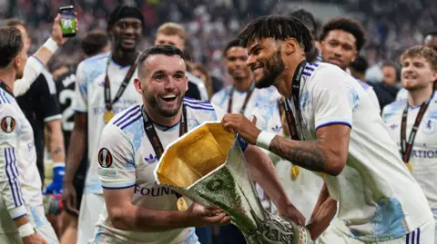 Aston Villa's John McGinn and Tyrone Mings lift the Europa League trophy 