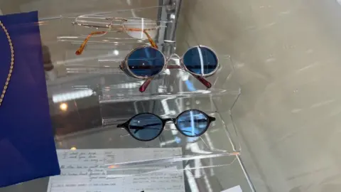 Three pairs of glasses, two are tinted blue, all are oval shaped.