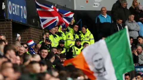 Reuters Police officers inside the stadium between flag waving Rangers and Celtic fans before a Scottish Cup match at Ibrox