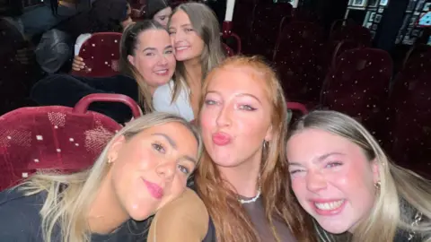 Alice Jenkins A group of four woman on a bus. They are smiling at the camera for a photograph