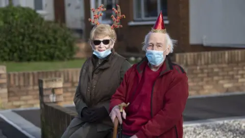 Getty Images A man and a woman in festive clothing celebrate Christmas Day in Cardiff, Wales