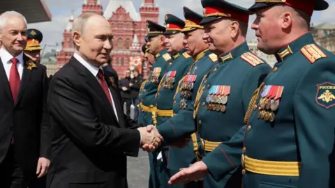 Putin shakes hands with participants in the Red Square military parade