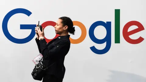 Getty Images A woman takes a selfie by a Google sign