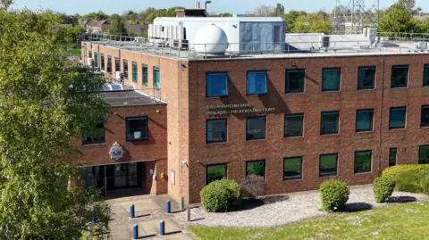 Ant Saddington/BBC A drone image of a red brick box-like building with rows of square windows over three floors. The lettering BEDFORDSHIRE POLICE HEADQUARTERS is on the brickwork.