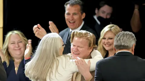 Getty Images Scott Stuber (back) applauding The Power of the Dog's Jane Campion and Jesse Plemons at the Directors Guild of America Awards earlier this month