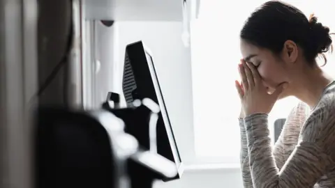 Getty Images A woman sitting at a computer looking really stressed