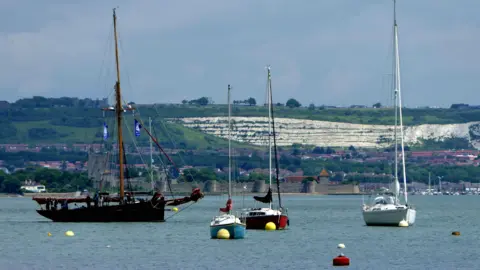 MONDAY - Boats moored off Portchester with a white cliff behind