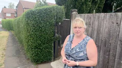 BBC Anna Gilkinson standing on a pavement next to her back gate