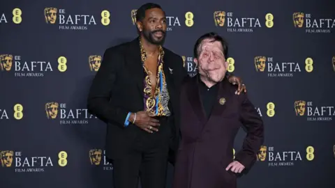 Getty Images Colman Domingo and Adam Pearson both in suits, Domingo is in a colourful shirt