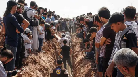AFP Members of the Syrian civil defence volunteers, also known as the White Helmets, bury their fellow comrades during a funeral in Sarmeen