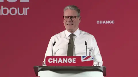 Sir Keir Starmer wearing a white shirt and a brown tie