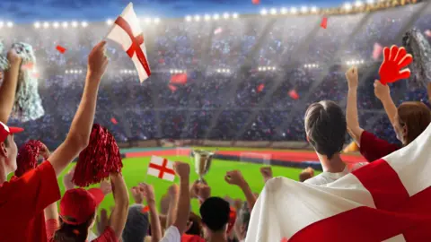 A football stadium with a large number of fans holding English flags