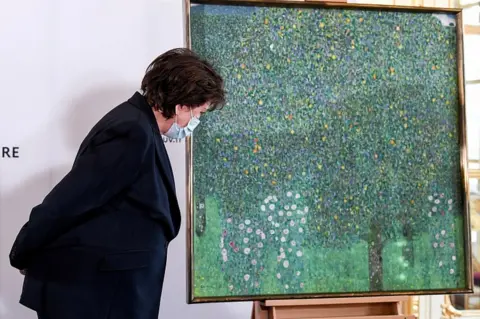 Reuters French Culture Minister Roselyne Bachelot stands next to the painting Rose Bushes under the Trees by Austrian painter Gustav Klimt, at the Musee d'Orsay in Paris, France March 15, 2021