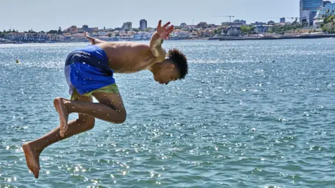 Getty Images A youngster dives from the wave breaker in Praia do Tamariz in Portugal, a popular spot with locals and tourists