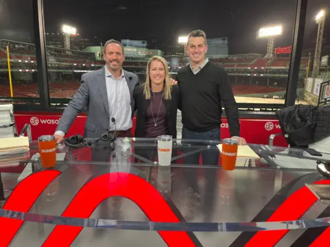Foto Carson Dugen, Center e dois comentários de esportes masculinos em frente ao estádio em ambos os lados do estádio