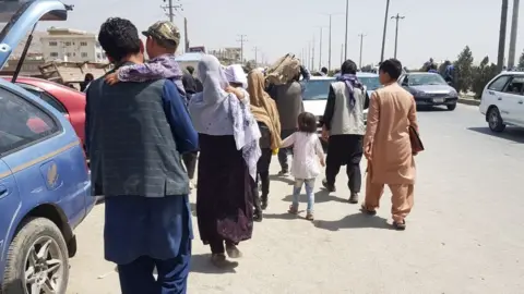 Getty Images Afghans waiting outside Hamid Karzai International Airport on 21 August