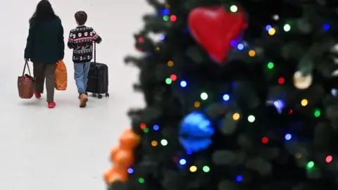 Commuters pass a decorated Christmas tree during the Christmas Eve getaway at Waterloo Station in London. 