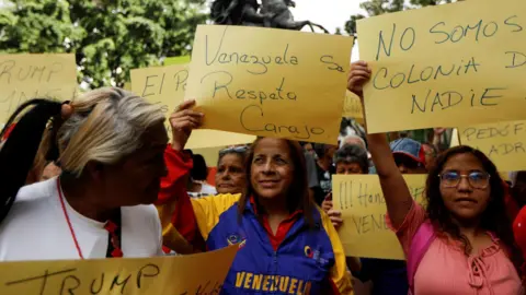 Reuters Government supporters hold signs reading "Venezuela commands respect "and "We are not anyone's colony "during a protest against U.S. President Donald Trump's order to blockade sanctioned oil tankers entering and leaving Venezuela, in Caracas, Venezuela, December 17