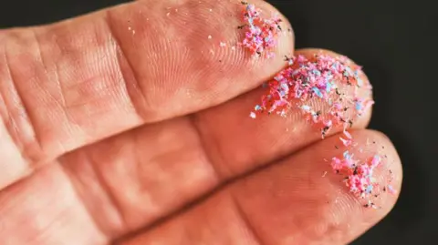 A hand with microplastics on the fingers.