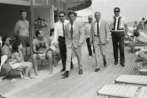 Terry O'Neill / Iconic Images Frank Sinatra with his minders and his stand in (who is wearing an identical outfit to him), arriving at Miami Beach while filming The Lady in Cement