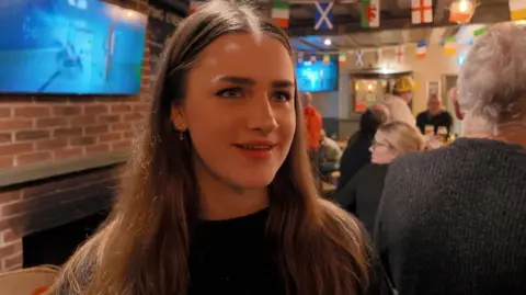 Tilly Shepheard stood in the pub with the TV behind her.