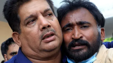 Samiullah, the father of a newborn who was killed in the PIMS hospital blaze, is comforted