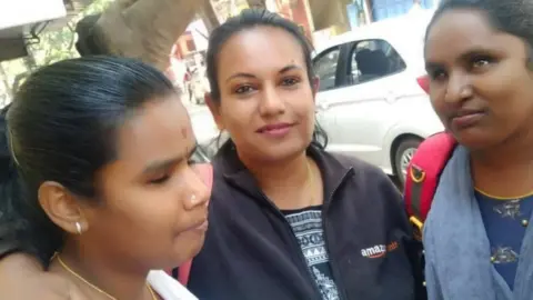 Pushpa Pushpa poses with two exam candidates who are visually impaired