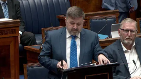 NI Assembly Health Minister Robin Swann speaking in the Northern Ireland Assembly