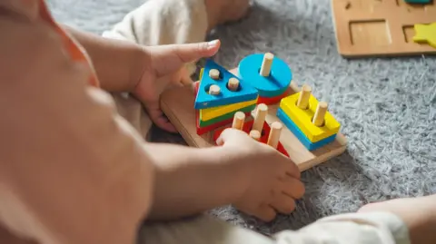 Getty Images un bebé juega con coloridos rompecabezas. Los bloques de madera en los cuadrados, círculos y triángulos se colocan sobre los tobillos en un simple juguete.
