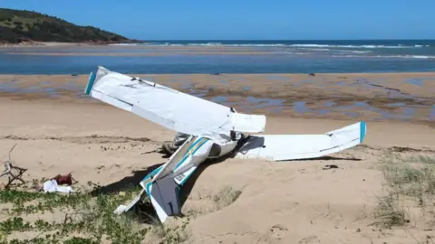 Australian Transport Safety Bureau A light plane which has crashed on sand with the ocean in the background