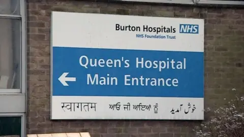NHS hospital sign reading Queen's Hospital Main Entrance