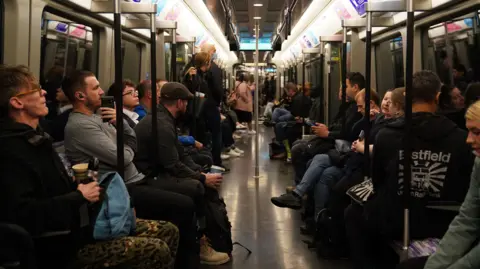 PA Media Passengers sitting in an Elizabeth Line train carriage