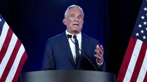 Getty Images RFK Jr behind a podium flanked by American flags