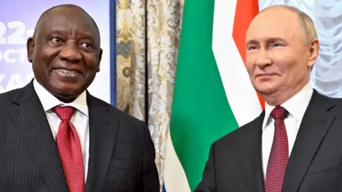 South African President Cyril Ramaphosa (L) in pinstriped dark grey suit and red tie next to Russian counterpart Vladimir Putin in grey suit and similar tie. Behind them can be seen part of the South African flag.