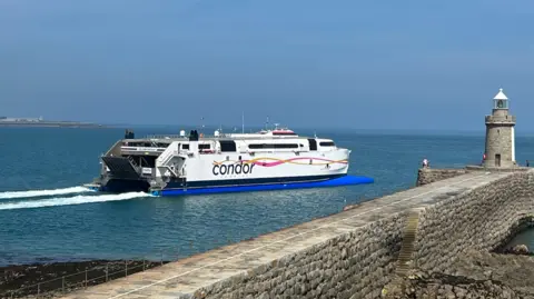 The Condor Voyager leaving St Peter Port harbour with a lighthouse to the right of the picture.