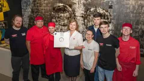 Mission Director of Strawberry Field, Major Kathy Versfeld holding the vinyl with members of the Salvation Army Steps to Work programme