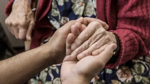 Getty Images Holding an older person's hand