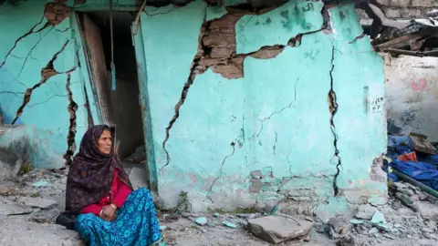 Getty Images A woman sits beside a cracked wall of her house at Joshimath in Chamoli district of India's Uttarakhand state on January 10, 2023.