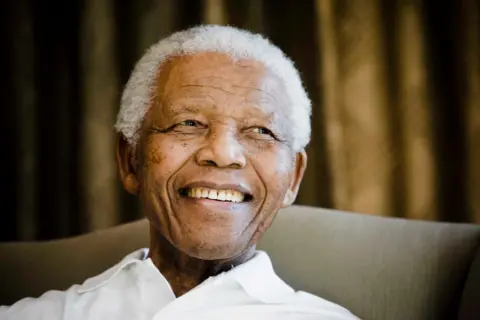 An older Nelson Mandela smiling during a BBC interview