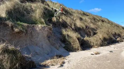 The picture shows steps dropping onto a beach coming to an abrupt end