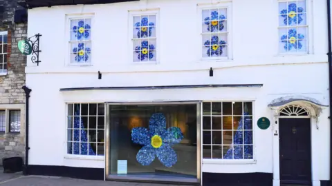A wide shot of the museum with the blue flowers shown in each of the windows of the building