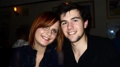 Emma Williams-Tully Emma Williams-Tully at age 20 with now husband Dan, both are wearing black and smiling at camera