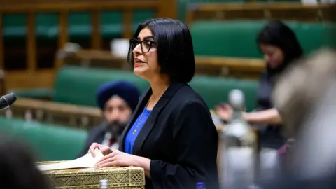 Home Secretary Shabana Mahmood in the Commons wearing a black suit jacket and blue shirt.