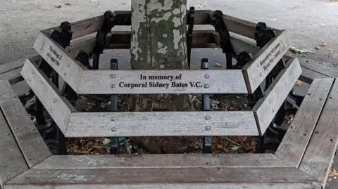 Bernhard Bauer Wooden park bench incribed with words "In memory of Corporal Sidney Bates VC"