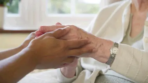 Getty Images a carer holding hands with a patient